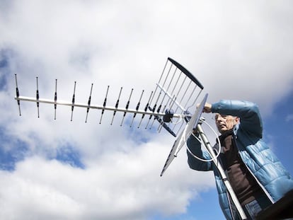 Un antenista cambia una antena antigua y resintoniza una nueva con amplificador de señal en una casa.