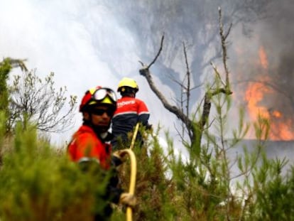 Dos bomberos con una manguera en el incendio declarado hoy en el t&eacute;rmino de Torre Manzanas.