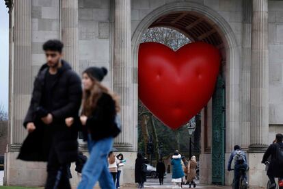 La gente pasa frente a un corazón inflable instalado para el día de San Valentín bajo Wellington Arch, cerca de Hyde Park, en el centro de Londres este lunes.