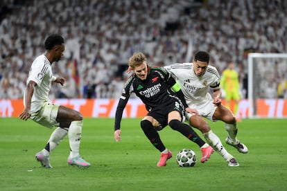 Martin Odegaard, del Arsenal, conduce el balón entre Vinicius Junior y Jude Bellingham.
