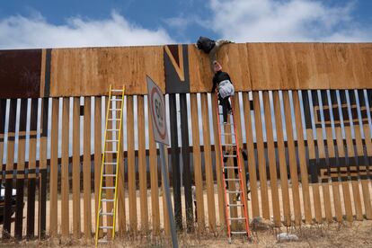 Dos migrantes saltan el muro fronterizo entre Tijuana y San Diego en junio de 2024.