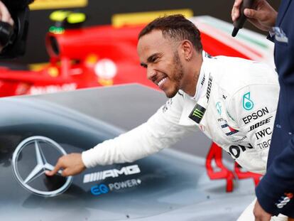 Lewis Hamilton posa junto al auto de Mercedes.