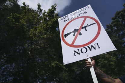 Un hombre sostiene una pancarta exigiendo que se prohíba la venta de armas de asalto.