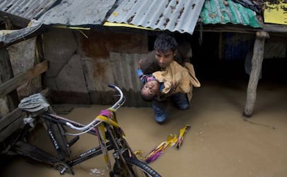 Un hombre traslada a un niño tras ser inundada su casa en un barrio de Srinagar, en Cachemira.