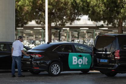 Vehículos VTC esperan la llegada de clientes bajo un puente en la entrada del aeropuerto de El Prat de Barcelona.