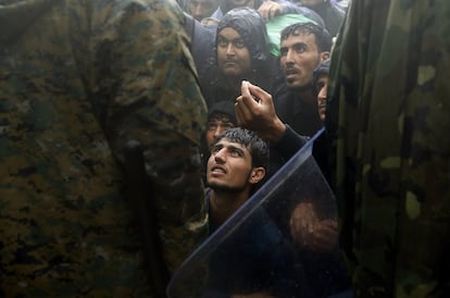 Refugiados suplicam aos policiais macedônios que lhes permita passar pela fronteira greco-macedônia, perto da vila de Idomeni.