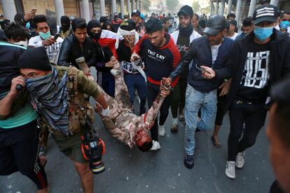 Varias personas trasladan a un soldado gravemente herido durante los enfrentamientos con manifestantes antigubernamentales durante las protestas en Bagdad (Irak).