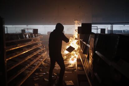 Colunas de fumaça saíam de alguns edifícios já desde o meio da tarde de sábado. Na imagem, um jovem queima produtos no interior de um supermercado de Mineápolis.