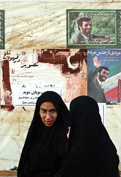 Dos iraníes pasan ante carteles de la campaña electoral en Teherán.