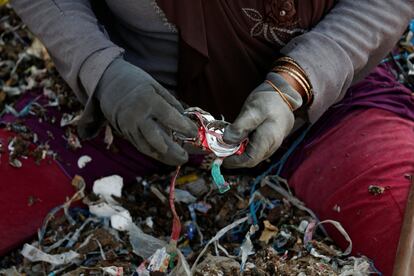 Si bien puede ser más lucrativo, las pilas de basura son una amenaza para la salud de los aldeanos, dicen los ambientalistas. La investigación realizada por el grupo ecologista ECOTON descubrió que los microplásticos contaminaron el agua subterránea en Bangun y en el cercano río Brantas que 5 millones de personas usaban para beber agua en el área. En la imagen, Kusmani, una mujer de 55 años que ha trabajado con residuos por más de 20 años, sostiene una lata usada mientras clasifica basura en el pueblo de Bangun en Mojokerto, provincia de Java Oriental, Indonesia.