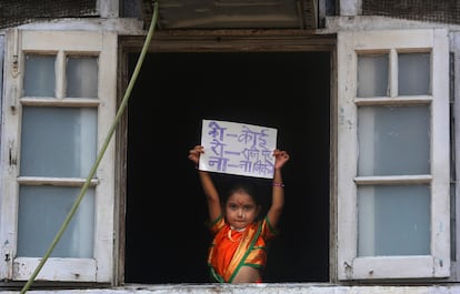 Menina indiana segura cartaz onde se lê "Ninguém deve sair de casa", em Mumbai.