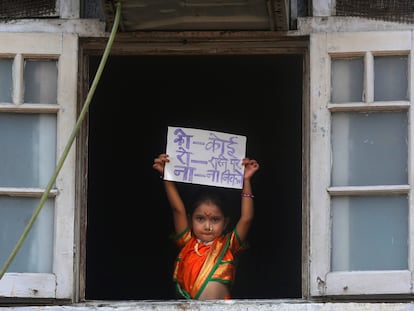 Menina indiana segura cartaz onde se lê "Ninguém deve sair de casa", em Mumbai.