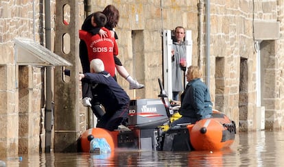 Unos bomberos evacúan a unos residentes de la localidad de Guincamp, en Francia. La borrasca Xynthia  inundó varias localidades en el oeste de Francia.