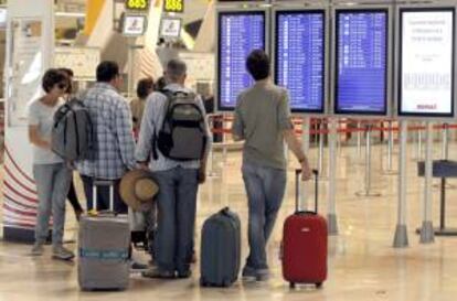 Varios pasajeros consultan paneles informativos esta tarde en la T4 del aeropuerto de Barajas. EFE/Archivo