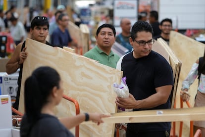 La gente compra madera para proteger sus ventanas de los fuertes vientos, en Cancún. 