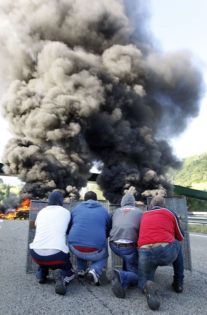 Un grupo de mineros, tras la barricada de neumáticos quemados creada en la autovía A-66.