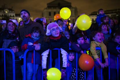 Varias personas con globos iluminados celebran la Hora del Planeta en Madrid, con el Teatro Real al fondo.