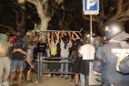 Un grupo de protestantes levanta una de las vallas del perímetro de seguridad.