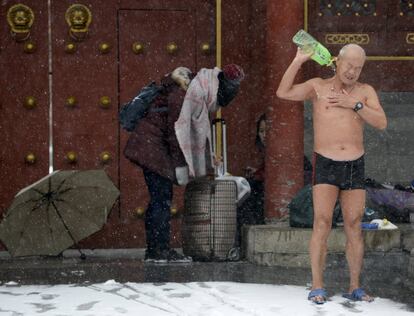 Un nadador se lava con una botella después de nadar en el lago Shichahai en medio de una fuerte nevada en Pekín (China).