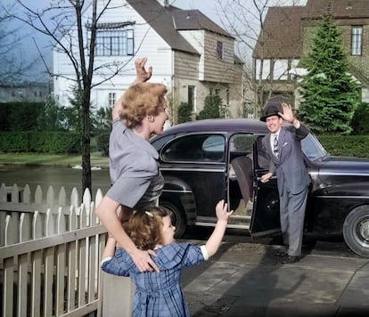 Una mujer y su hija saludan al padre en una urbanización en los años cincuenta.
