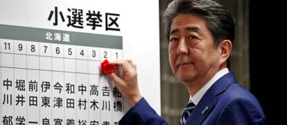 Shinzo Abe, primer ministro de Jap&oacute;n, coloca una rosa sobre el nombre de un candidato que ha obtenido esca&ntilde;o, durante el recuento electoral en Tokio. 