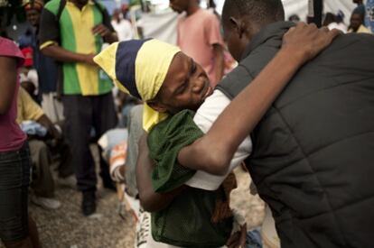 Un hombre ayuda a un enfermo de cólera en el hospital de Saint Marc, en Haití.