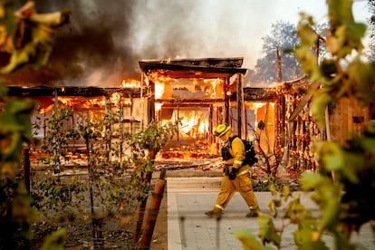 Woodbridge firefighter Joe Zurilgen passes a burning home as the Kincade Fire rages in Healdsburg, Calif., on Oct. 27, 2019.
