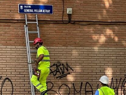 Dos operarios colocan el nuevo rótulo de la calle General Millán Astray en el callejero de Madrid.