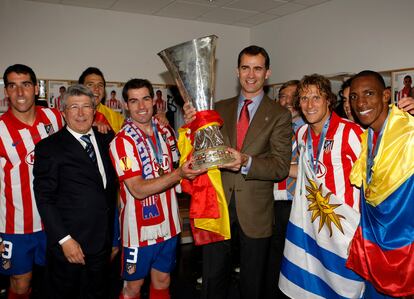 El Príncipe de Asturias posa en los vestuarios del estadio con la copa del título de la Liga Europa conquistado por el Atlético de Madrid en los Hamburgo frente al Fulham, acompañado del presidente del equipo, Enrique Cerezo , el capitán, Antonio López  y varios jugadores.