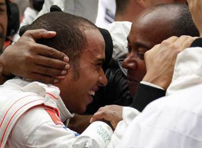 Lewis Hamilton es felicitado por su padre, tras el triunfo de ayer.