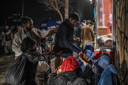 Un hombre daba un poco de comida a unas afganas sentadas delante de una panadería, el pasado jueves en Kabul.