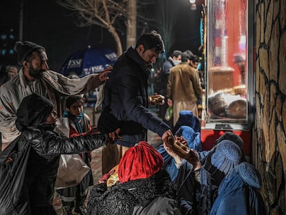 Un hombre daba un poco de comida a unas afganas sentadas delante de una panadería, el pasado jueves en Kabul.