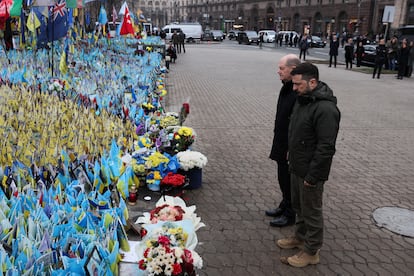 El presidente de Ucrania, Volodímir Zelenski, y el canciller alemán, Olaf Scholz, visitan un lugar conmemorativo improvisado que muestra banderas ucranias con los nombres de los militares caídos, en la plaza de la Independencia, en Kiev, el 2 de diciembre.