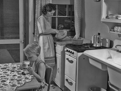 Una mujer prepara la comida en la cocina junto a su hijo.