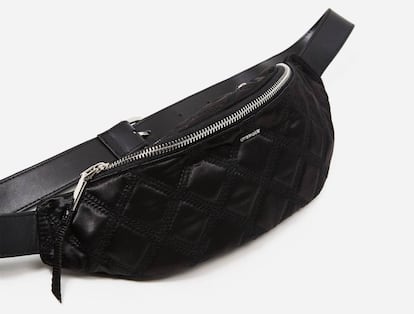 Una riñonera acolchada. Este bolso riñonera, lanzado recientemente por Uterqüe, la marca de alta gama de Inditex, está fabricado en nailon y tiene un revestimiento de materiales acolchados. Con un diseño con un solo compartimento y un bolsillo lateral, forma parte de la última colección de la compañía, presentada durante esta semana. El logo de la marca está bordado como un pequeño detalle en el bolsillo frontal, y en la parte posterior dispone de cremalleras metálicas en tonalidad plateada. Presenta tira ajustable en piel de alta calidad. El modelo está disponible únicamente en color negro.  Precio: 59 euros.