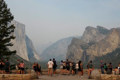 Visitantes del parque toman fotos y selfis en uno de los puntos más fotogénicos del parque nacional Yosemite, Tunnel View, a pesar del humo que opaca la vista.