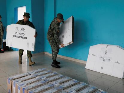 Soldados del ejército ecuatoriano entregan cajas electorales en una mesa electoral.