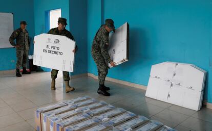 Soldados del ejército ecuatoriano entregan cajas electorales en una mesa electoral.