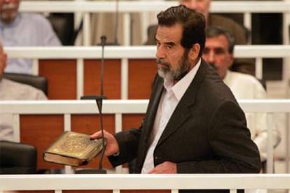 Sadam Husein muestra el Corán durante su comparecencia de ayer ante el tribunal que le juzga en Bagdad.