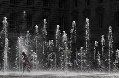 Transeúntes se refrescan en una de las fuentes del centro de Londres.