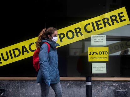 Un mujer pasa, este lunes, frente a una tienda en fase de liquidación en Córdoba.