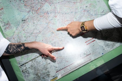 Dos personas buscan su dirección en un mapa de una marquesina de autobús.