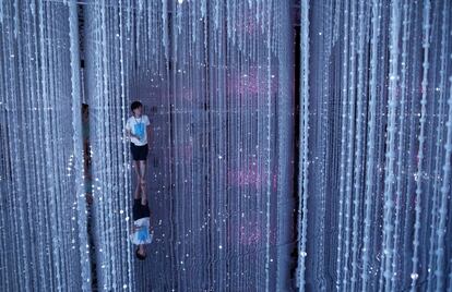 Una trabajadora camina a través de las luces LED de la instalación digital 'Wander through the Crystal Universe' ('Vagar por el universo de cristal) presentado por el colectivo artístico teamLab en el evento 'A World of Wonders' en Tokio (Japón).