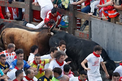 Un toro embiste a un corredor durante el séptimo encierro de los Sanfermines.
