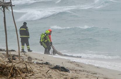 Personal de rescate trasladan el cuerpo de un migrante en la playa.