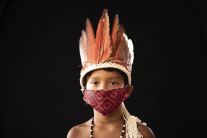 Elano de Souza, de seis años, del grupo étnico indígena sateré mawé, posa para un retrato con el vestido tradicional de su tribu y una máscara facia en Gaviao, cerca de Manaos, Brasil.