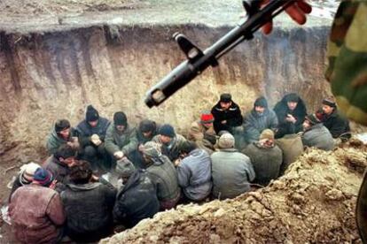 Un soldado ruso custodia a varios detenidos en Grozni durante redadas de las fuerzas de seguridad, en febrero de 2000.