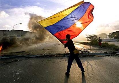 Un opositor a Chávez ondea una bandera mientras la policía lanza gases lacrimógenos.