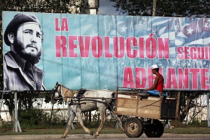 Un hombre pasa en un carro tirado por un caballo junto a un cartel de Fidel Castro en La Habana.