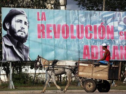 Un hombre pasa en un carro tirado por un caballo junto a un cartel de Fidel Castro en La Habana.